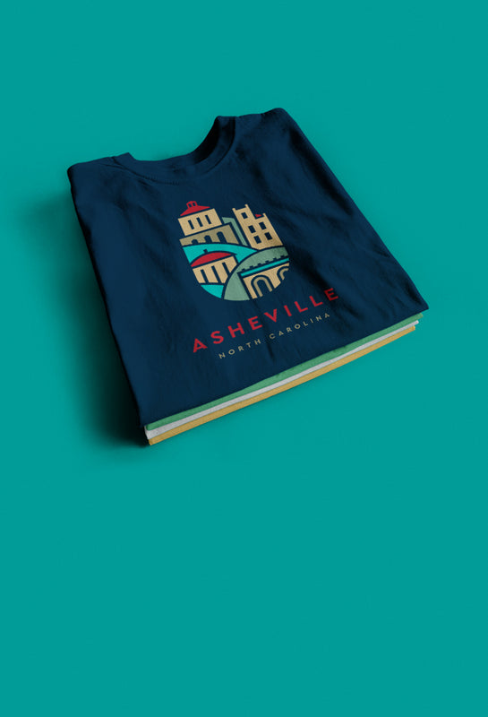Stack of Asheville graphic t-shirts featuring one with downtown illustration
