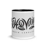 white coffee mug with "Asheville" written in custom lettering. Black interior and handle.